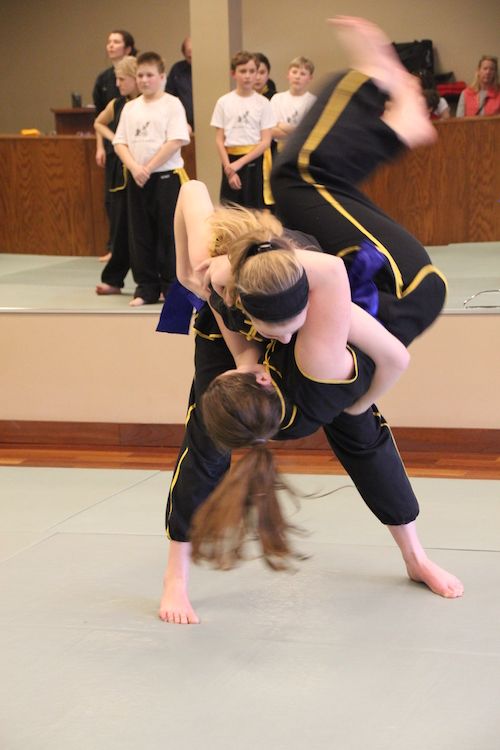 One young student practices throwing another student over their hip.
